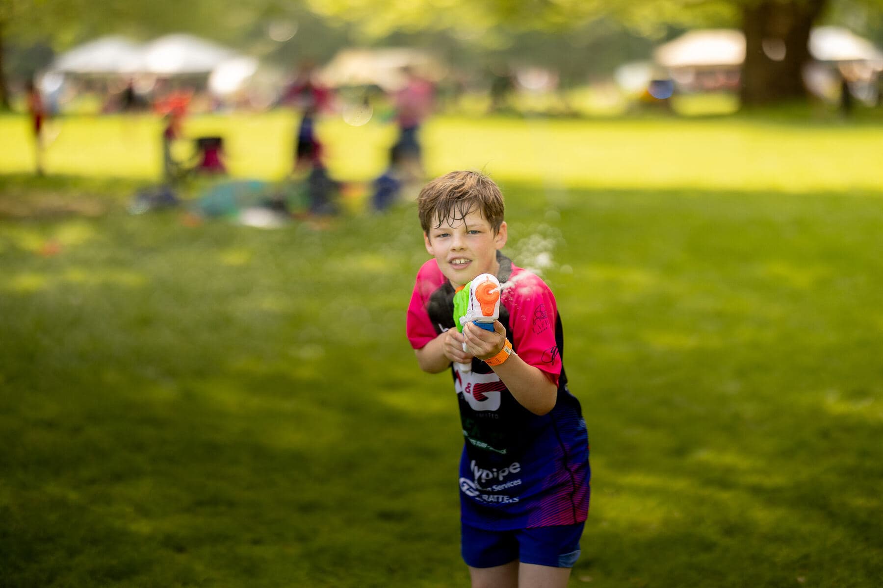 A young player in club kit eating an ice cream on the grass between matches
