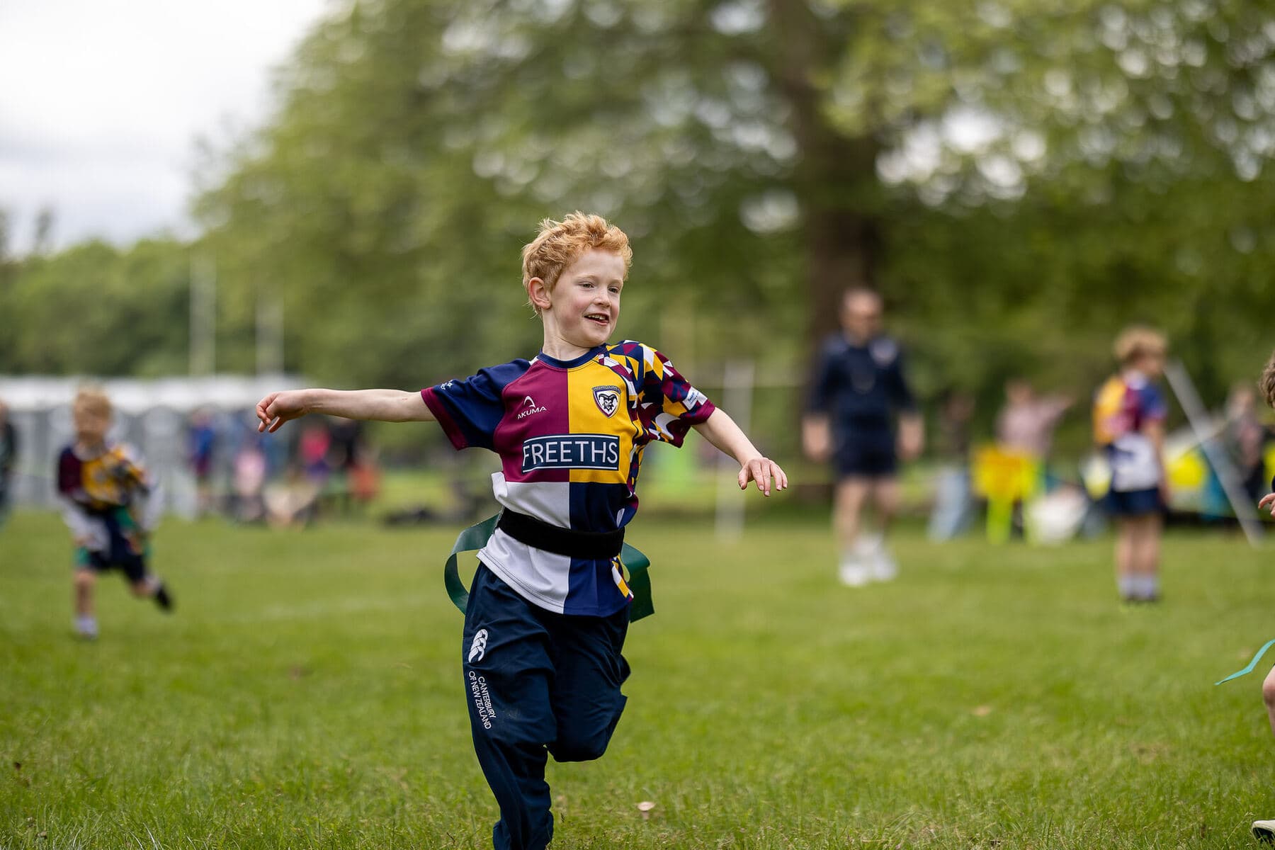 A young player in club kit running with the ball across a sunlit pitch