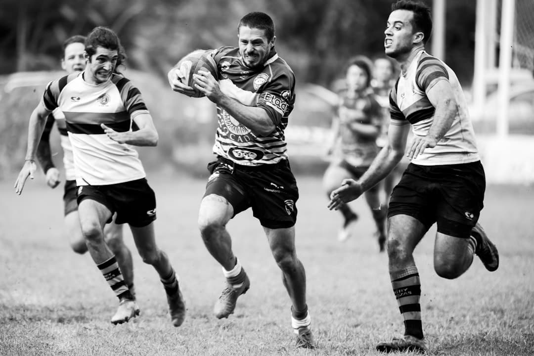An adult player carrying the ball into contact in a black-and-white match photo