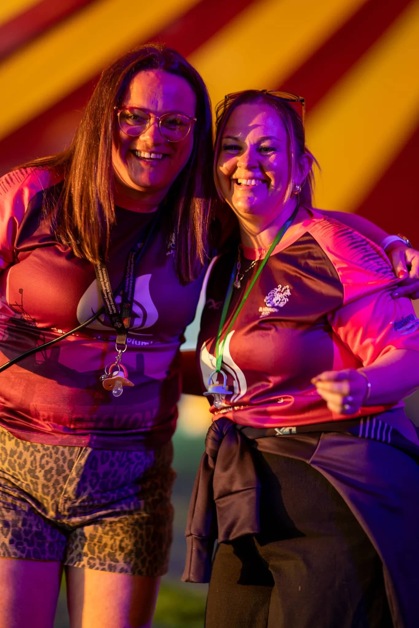 Two women laughing together in the big top on a Revel festival evening